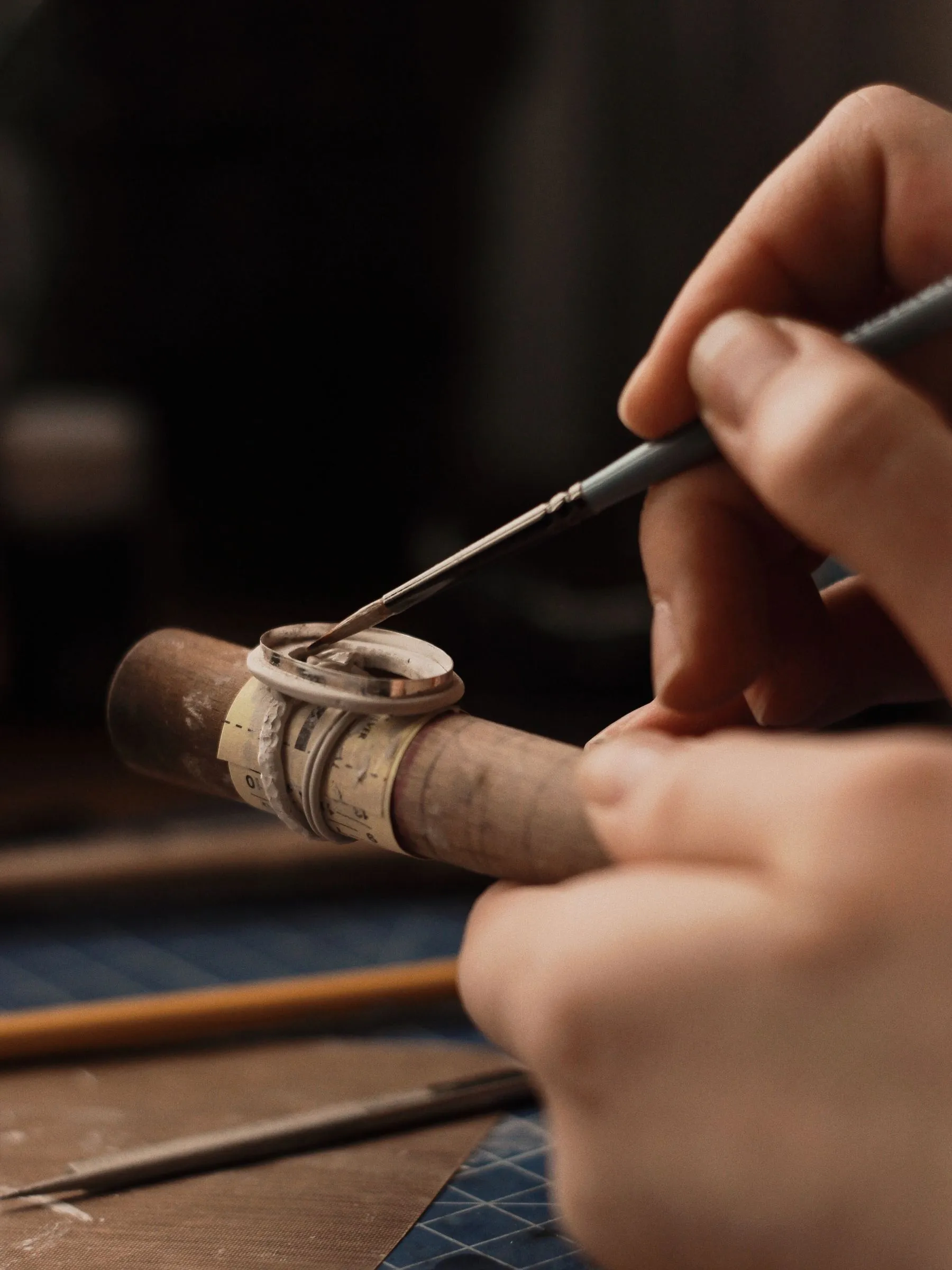 A jeweler filing a ring held in a wooden ring clamp