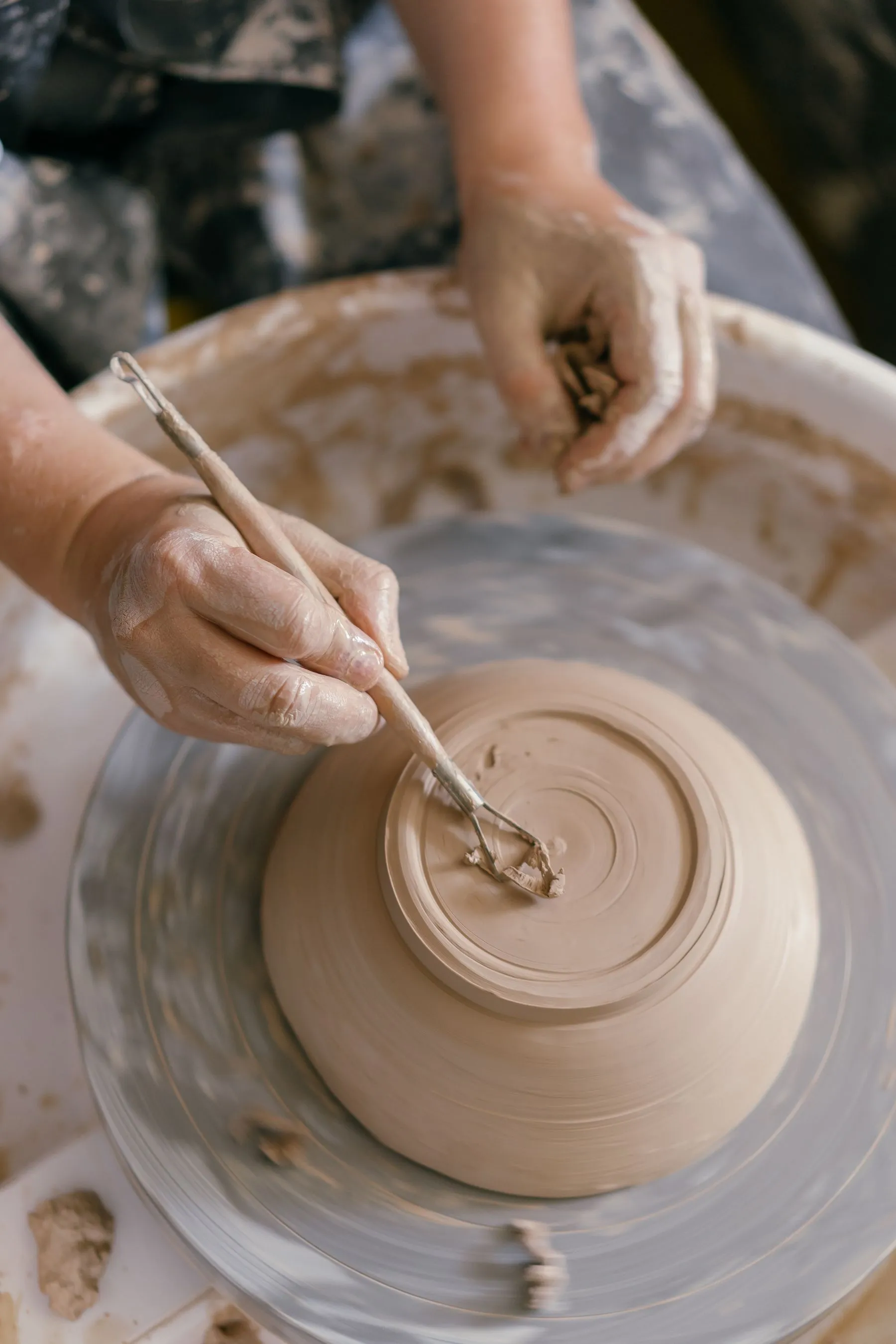 A potter trimming the foot of a clay bowl on a spinning wheel